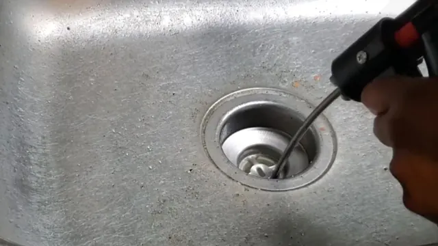 Cable tool entering a stainless steel sink drain.