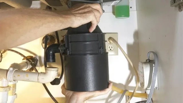 Hands lifting a garbage disposal unit into place under a sink.